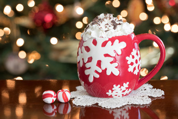 Obraz na płótnie Canvas Christmas photograph of a red cup of hot chocolate in front of the Christmas tree