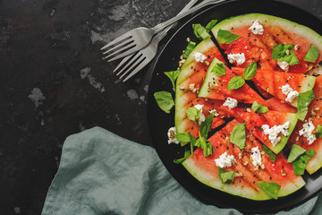 Grilled watermelon with cheese, basil and nuts on a concrete dark background. Fresh Watermelon Salad. Top view, overhead, flat lay.