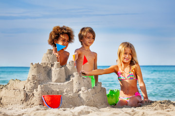Happy friends making sandcastle on the beach