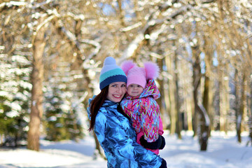 Mother with a little daughter on a walk in the woods on a snowy winter day. 