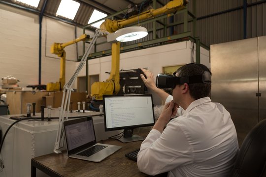 Robotics engineer using virtual reality headset at desk