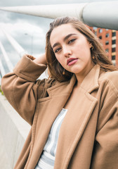 Fototapeta premium Beautiful colombian woman sits and poses in urban setting - red gold hair and leading lines
