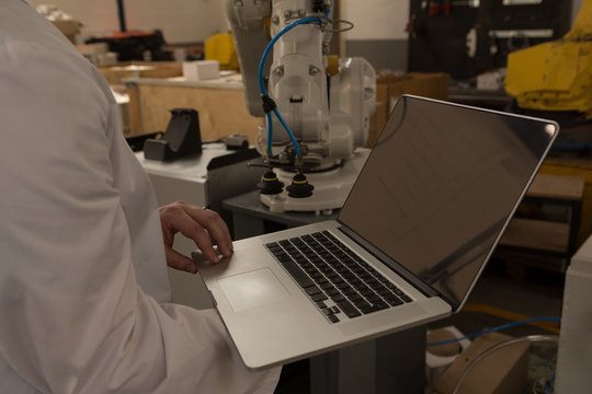 Robotics engineer using laptop in warehouse