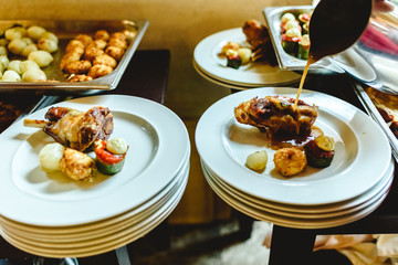 Waiters of a catering company plating the main course of a business lunch.