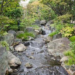 Nature background with view of traditional Japanese garden in Kanazawa, Japan, with rocks and artificial waterfall in November.