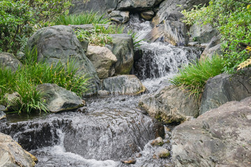 Nature background with view of traditional Japanese garden in Kanazawa, Japan, with rocks and artificial waterfall in November.