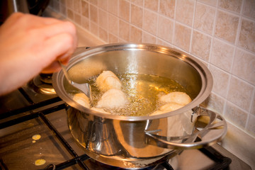 Woman's hands that Adjusting the Dough Friying in a Pot during the Preparation of an Italian Christmas Traditional Dish called Pettole