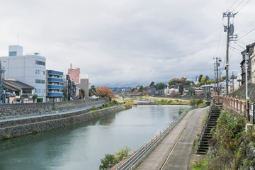 Obraz premium Urban or park background featuring Saigawa river and bridges across in residential district of Kanazawa, Japan, in cloudy autumn day in November. 