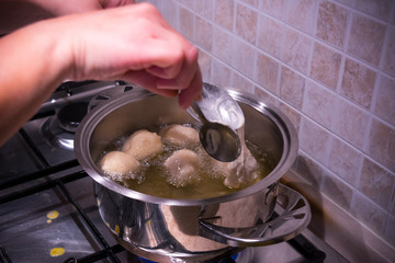 Woman's hands that make the Dough Slip from a Spoon into the Pot during the Preparation of an Italian Christmas Traditional Dish called Pettole
