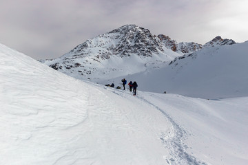 Some snowshoe hikers walk through the snow-covered Alps in winter in the canton of Graubünden in Switzerland.