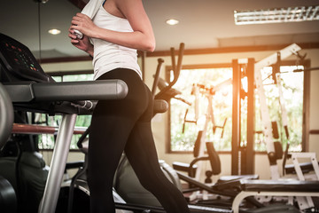 Fototapeta na wymiar Young girl running on treadmill at gym