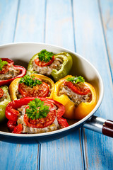 Stuffed peppers in frying pan on wooden table