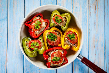 Stuffed peppers in frying pan on wooden table