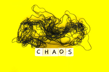 Word Chaos made of wooden cubes on the yellow background.