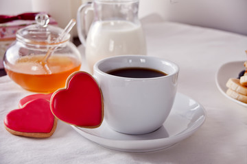 Coffee and a heart shaped cookies, honey, milk and waffles