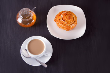 Coffee and cinnabon with honey on the wooden table