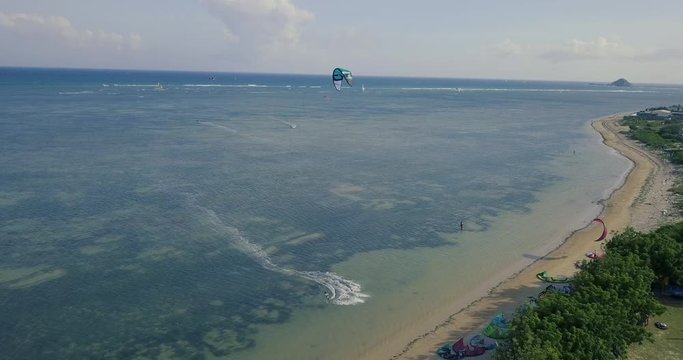 Aerial view of kiteboarding, kitesurfing. Extreme sports kitesurfing in tropical blue ocean, clear beach. Aerial views, top view from drone of kitesurfing on the waves of the beautiful sea
