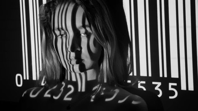 UPC code projected onto attractive young womans face. Black and white.