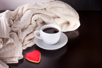 Cup of coffee and heart shaped cookie on the wooden table