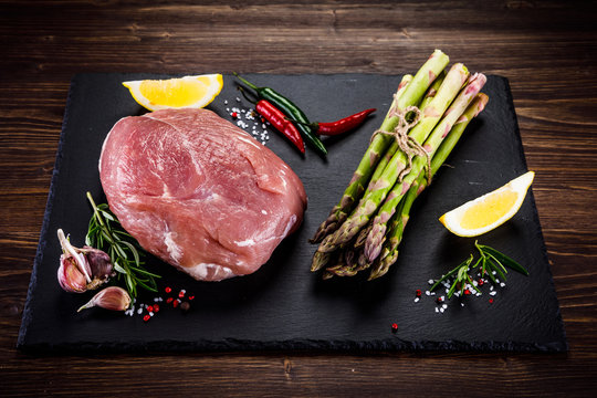 Fresh raw pork with vegetables on cutting board on wooden background