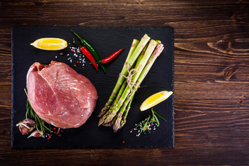 Fresh raw pork with vegetables on cutting board on wooden background