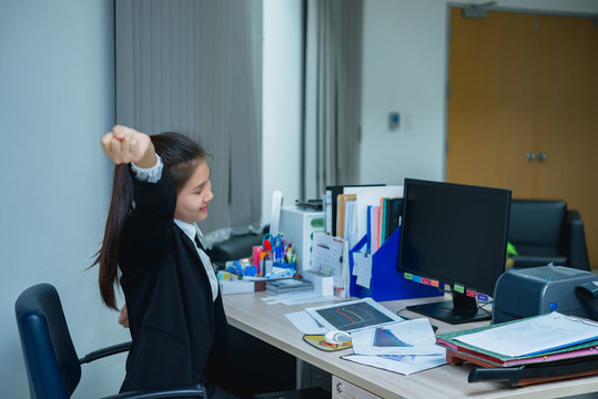 Asian officer woman stretching body at the desk of office from back angle,Thailand people,Businesswoman tired from hard work