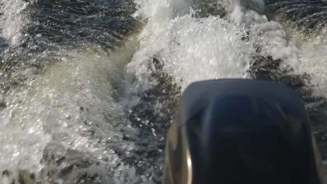 Slow motion motorboat wake. Closeup of patterns in the water. Defocused motor cover.