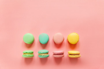 Sweet almond colorful pink blue yellow green macaron or macaroon dessert cake isolated on trendy pink pastel background. French sweet cookie. Minimal food bakery concept. Flat lay top view copy space
