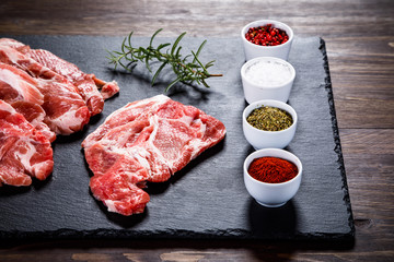 Raw beefsteaks on black stone on wooden background