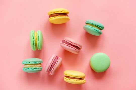 Sweet almond colorful pink blue yellow green macaron or macaroon dessert cake isolated on trendy pink pastel background. French sweet cookie. Minimal food bakery concept. Flat lay top view copy space