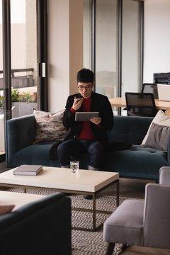 Businessman talking on mobile phone while using digital tablet in office