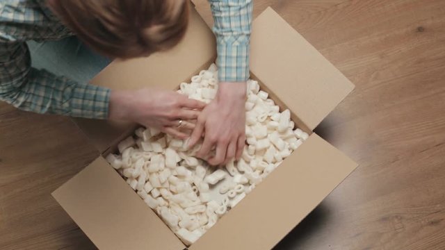 A young woman opens a parcel containing a heart shaped gift.