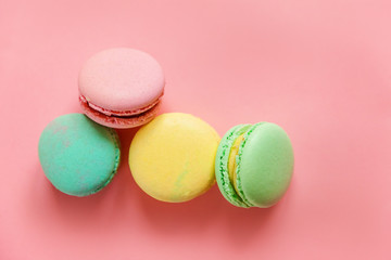 Sweet almond colorful pink blue yellow green macaron or macaroon dessert cake isolated on trendy pink pastel background. French sweet cookie. Minimal food bakery concept. Flat lay top view copy space