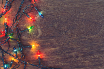 Colorful christmas lights over dark wooden background. Flat lay, with copy space