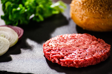 Fresh raw steak on black stone plate with vegetables