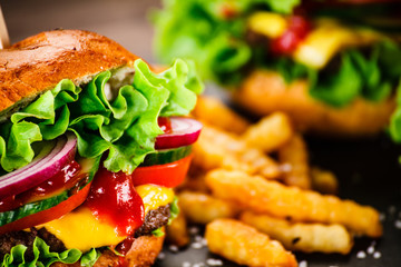Tasty cheeseburgers with french fries served on black stone