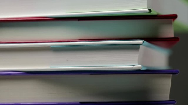 Extreme closeup footage of stacked colorful books spinning from left to right.