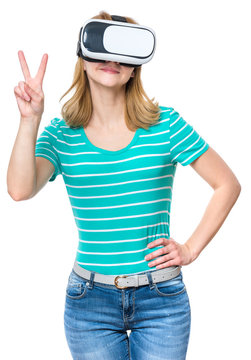 Happy Woman Wearing Virtual Reality Goggles Watching Movies Or Playing Video Games, Isolated On White Background. Smiling Girl Looking In VR Glasses And Making Victory Sign Gesture.