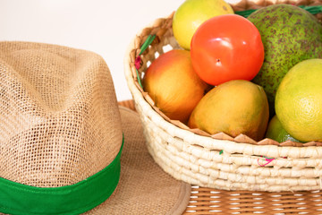 Basket of fruit and straw hat on the table. Agriculture concept image.