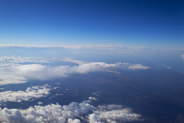 Fototapeta na wymiar view from the window of the plane to the cumulus clouds and the infinitely blue sky