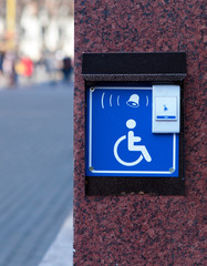 Handicapped access entrance pad mounted to a wall. Sign a button for a visa for people with...