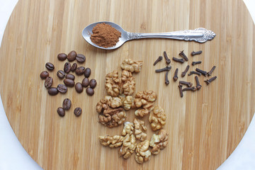 walnuts, coffee beans, clove seasoning, and a spoon of ground cinnamon on a kitchen board