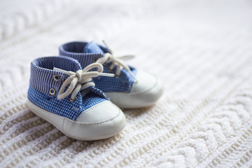 Cute baby boy blue sneakers on white knitted fabric. - obrazy, fototapety, plakaty