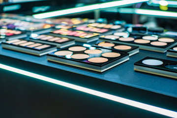 Cosmetics on the shop window with a variety of colors and shades, mascara, powder, paint for beauty and makeup. Consumerism, retail and purchase concept.