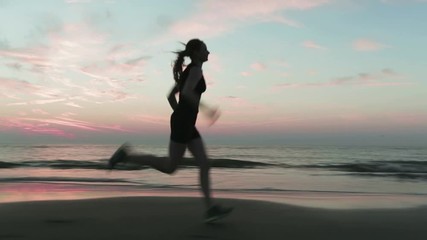 Active sports - young woman runs on a seashore sandy beach by sunset. - Powered by Adobe