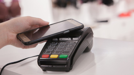 Woman using NFC technology for payment in the shop