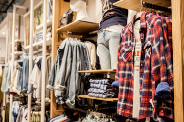 Fototapeta premium Shorts,shirts, T-shirts and jacket on the store shelf. Fashionable clothes on the shelves in the store. Showcase, sale, shopping. Luxury and fashionable brand new interior of the cloth store