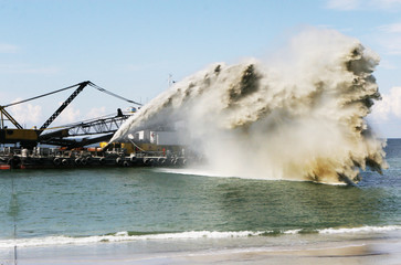 Work dredger dredging with sand washing on beaches. Special dredging hose for sand to create new...