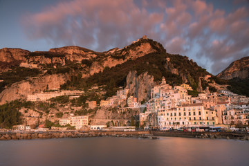 Obraz premium Wybrzeże Amalfi w ciepłym porannym świetle z pięknymi różowymi chmurami i zamazaną wodą morską