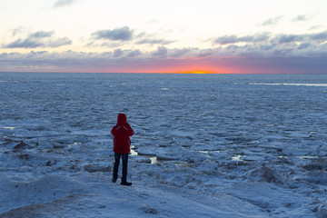 a man taking picture of a sunset. View from back